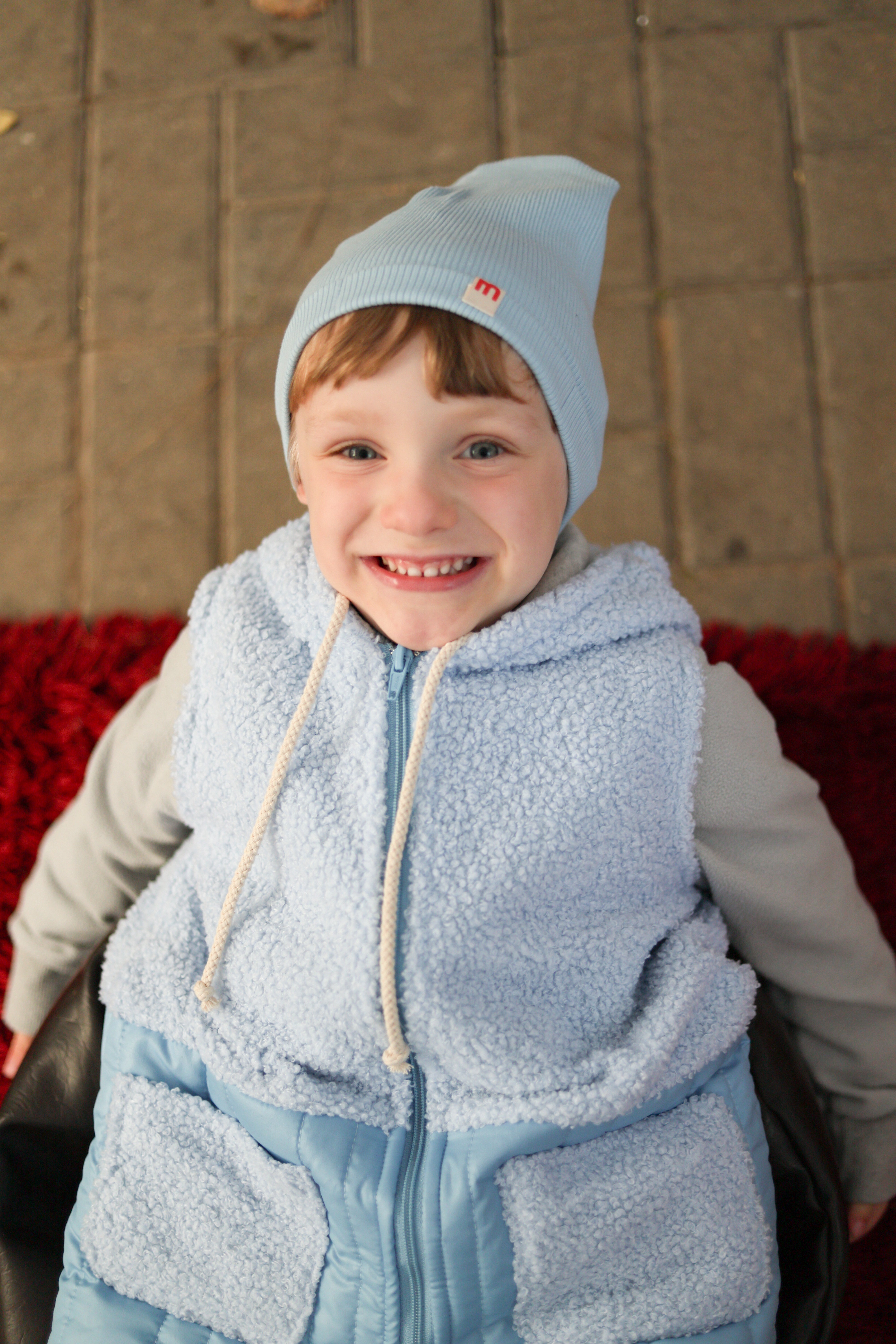 A boy in a blue hat and blue Teddy vest