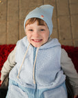 A boy in a blue hat and blue Teddy vest