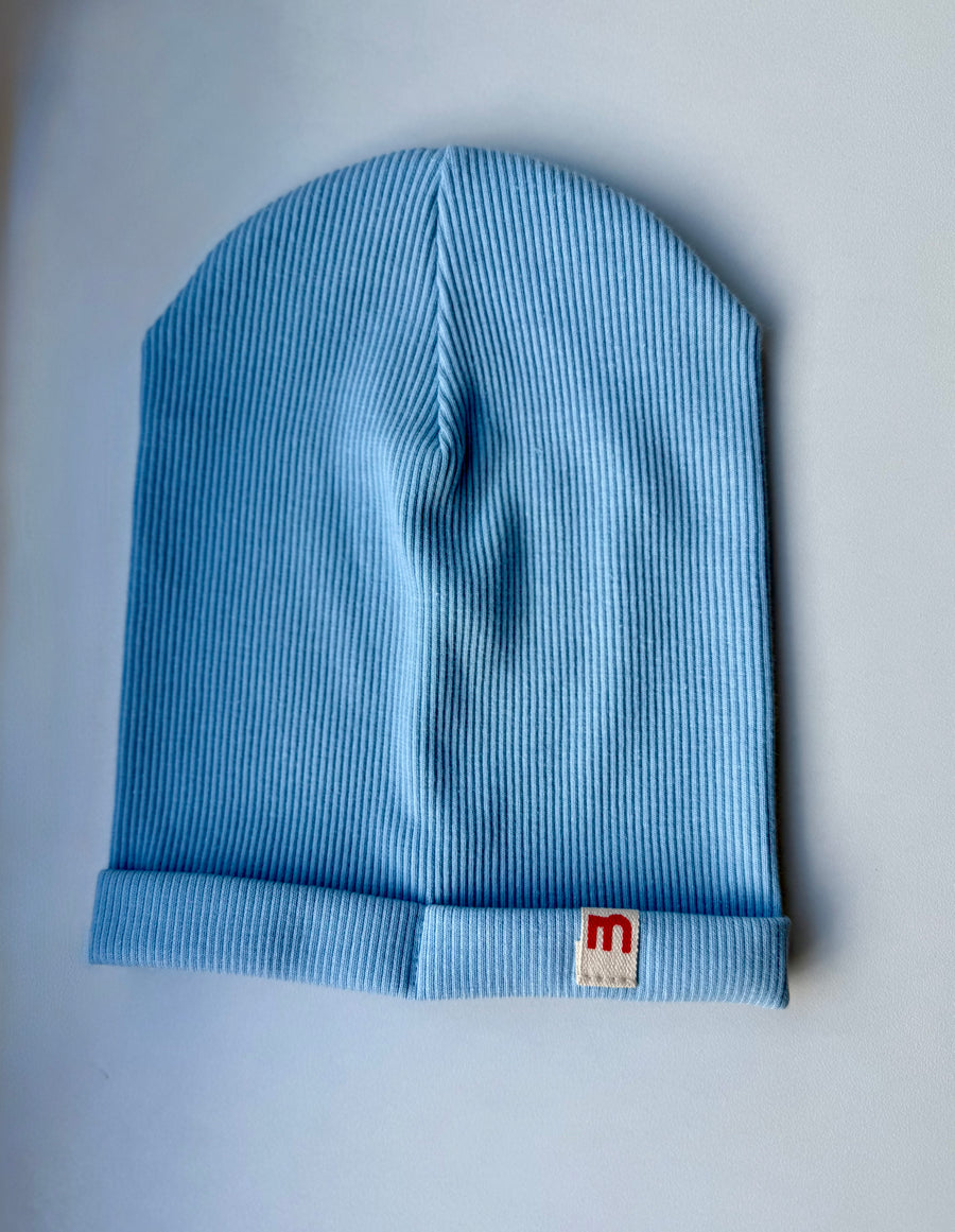 Blue single rib cotton  hat with a visible brand logo on a light gray background